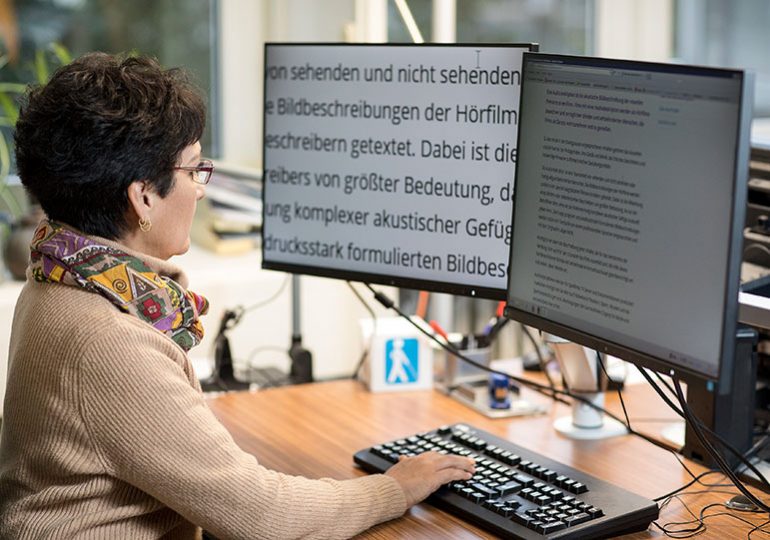 Frau arbeitet an einem Bildschirm mit großer Schrift