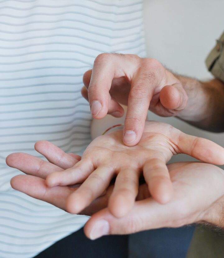 Zwei Personen kommunizieren mithilfe des Lorm-Alphabets, indem die eine in die Handfläche der anderen tastet.